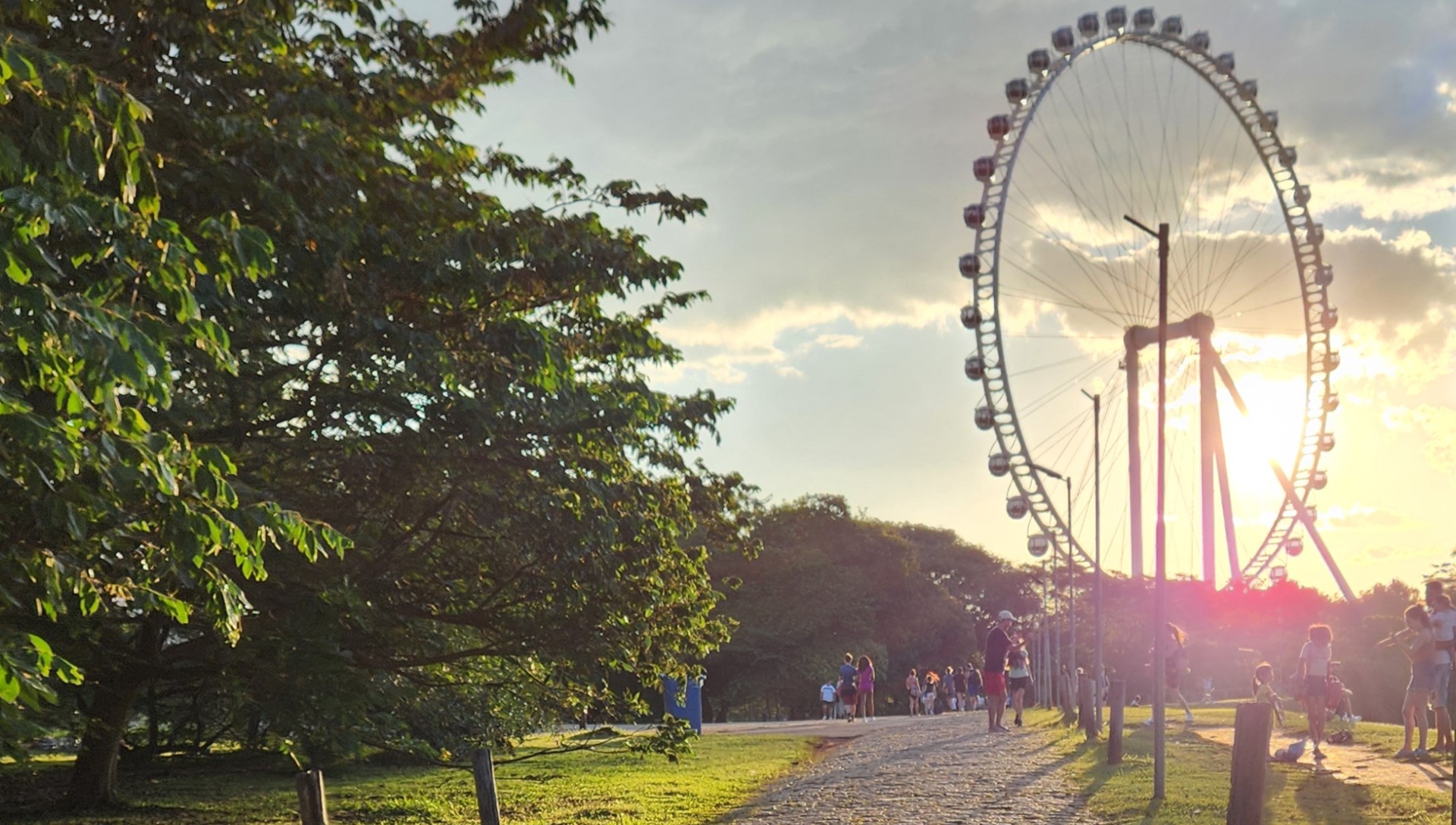 Foto sem filtros mostra o caminho até uma roda gigante ao pôr do sol, fazendo referência ao onboarding para uma experiência de sucesso, sem obstáculos.