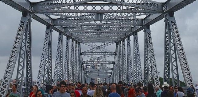 Foto mostra muitas pessoas andando sobre uma ponte em sua inauguração, fazendo referência aos vários possíveis dados, métricas e indicadores que podemos encontrar no caminho para o sucesso dos clientes.